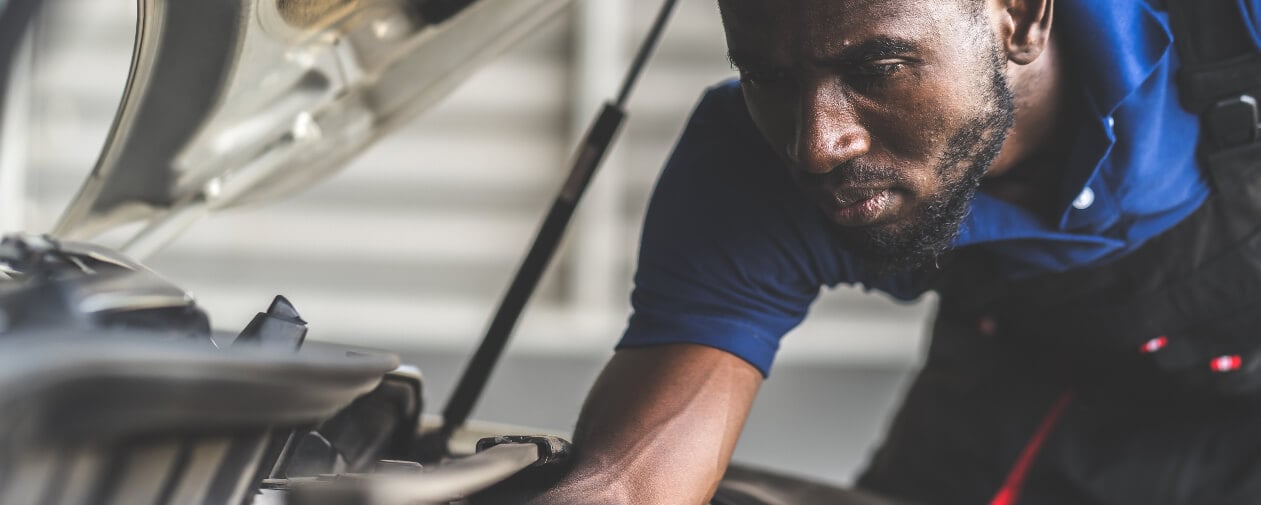 Uniformed young man working under the hood of a car