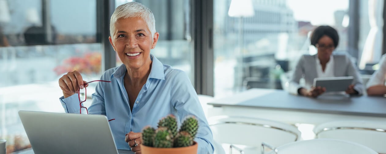 Seasoned business woman in her office smiling at camera