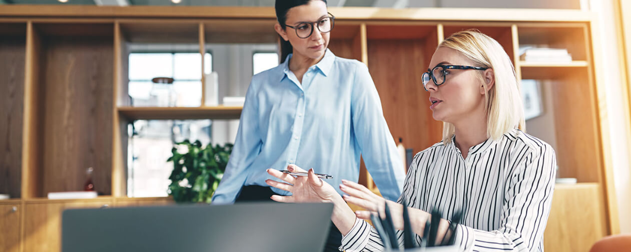 Focused young businesswoman explaining an idea with a coworker listening during a meeting together in an office