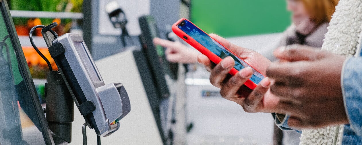 Customers using self checkout machines in retail store