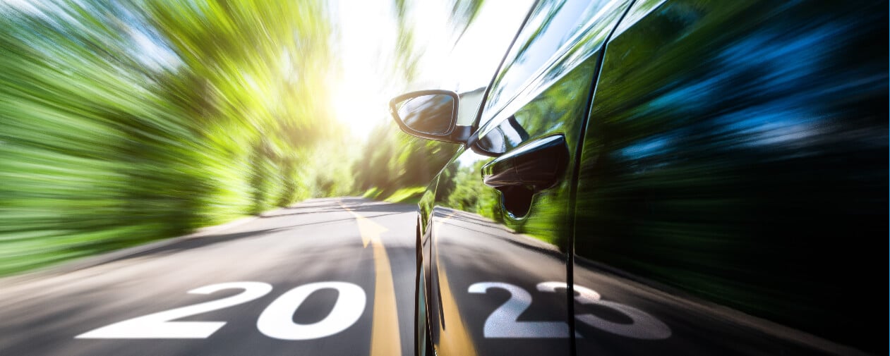 Car in motion blur driving to forest with new year number 2023 and arrow sign on the road