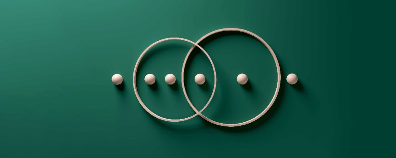 Crossing wooden rings with spheres in a row on green background.