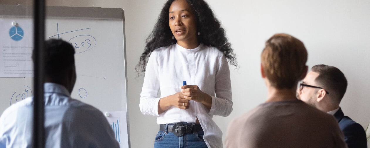 A person standing in front of a whiteboard in discussion with team