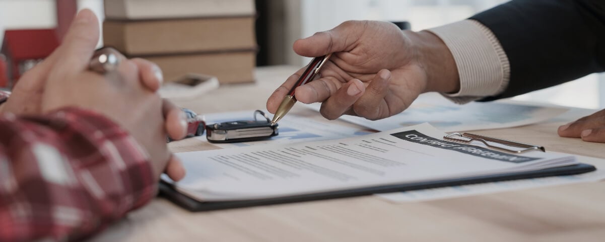 F&I team member working with a customer in his office with financing contract and car keys on desk