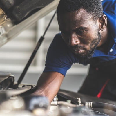 Uniformed young man working under the hood of a car