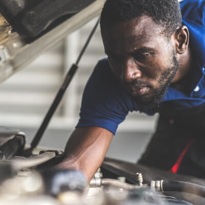 Auto Technician Uniformed young man working under the hood of a car